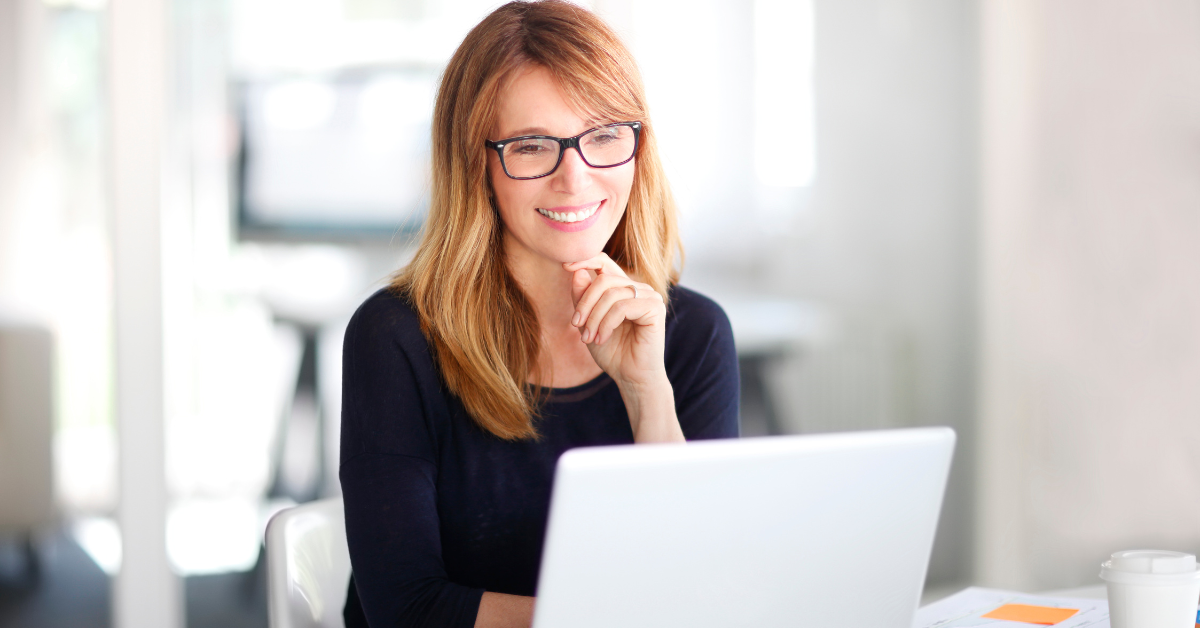 A woman reading at her laptop on How to file a 1099 NEC.