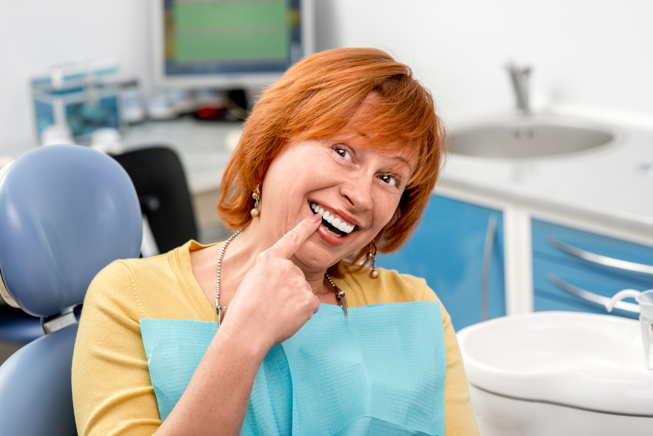 A woman with red hair that had a dental implant placed next to her natural teeth