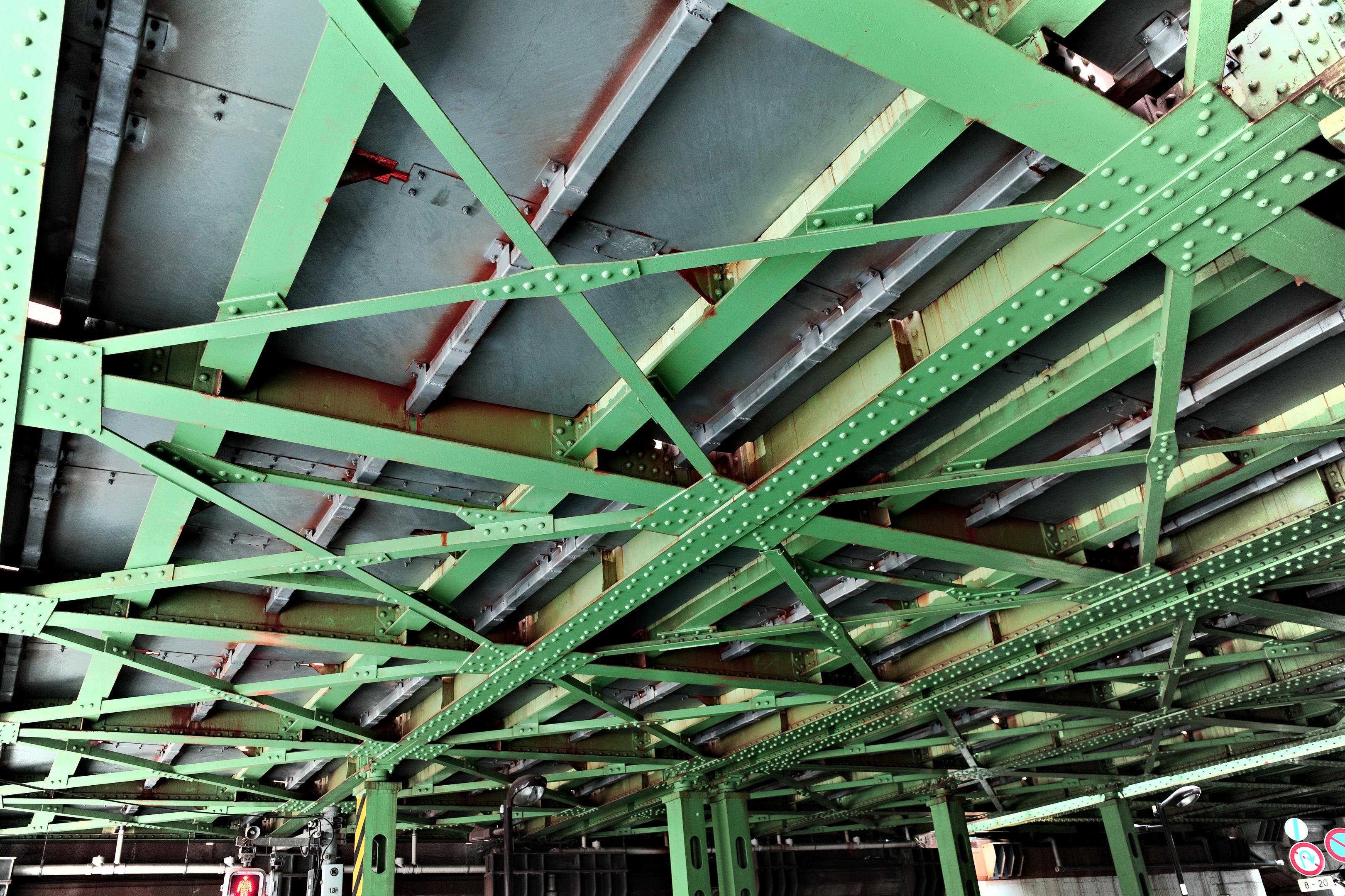 Riveted steel beam connections and cross-bracing viewed from below, showing precise alignment of structural members