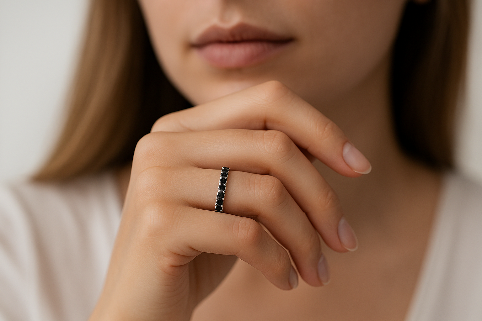 Deimantinė juostelė su juodais deimantais ant stilingos moters rankos, šviesiame fone.