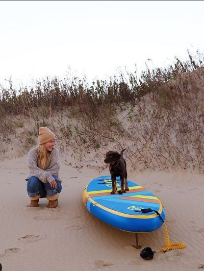 Adorable puppy on a Glide Inflatable Paddle Board on a Sandy bBeach
