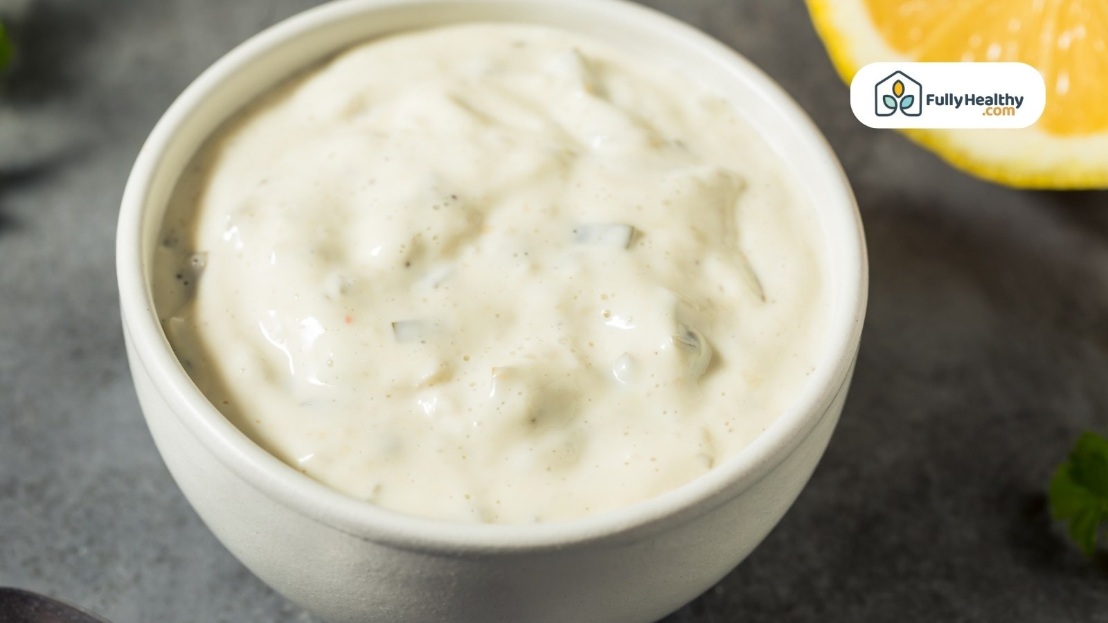 Small white bowl of creamy tartar sauce with lemon slice
