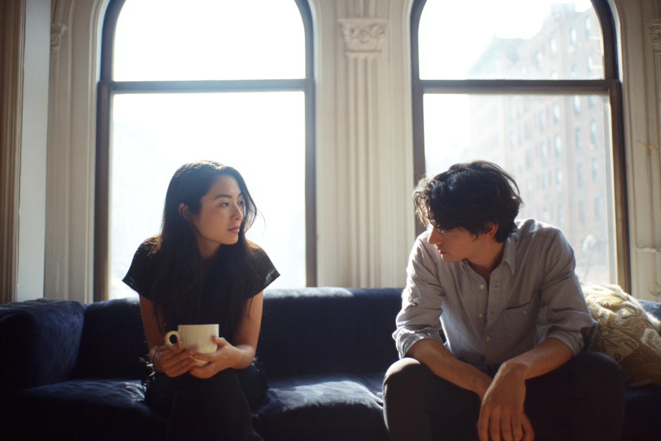 Attractive young heterosexual interracial couple in a quiet conversation in their Upper West Side living room, representing the moment of a bid for connection that Gottman Method therapy at New York Therapy teaches couples to recognize and respond to.