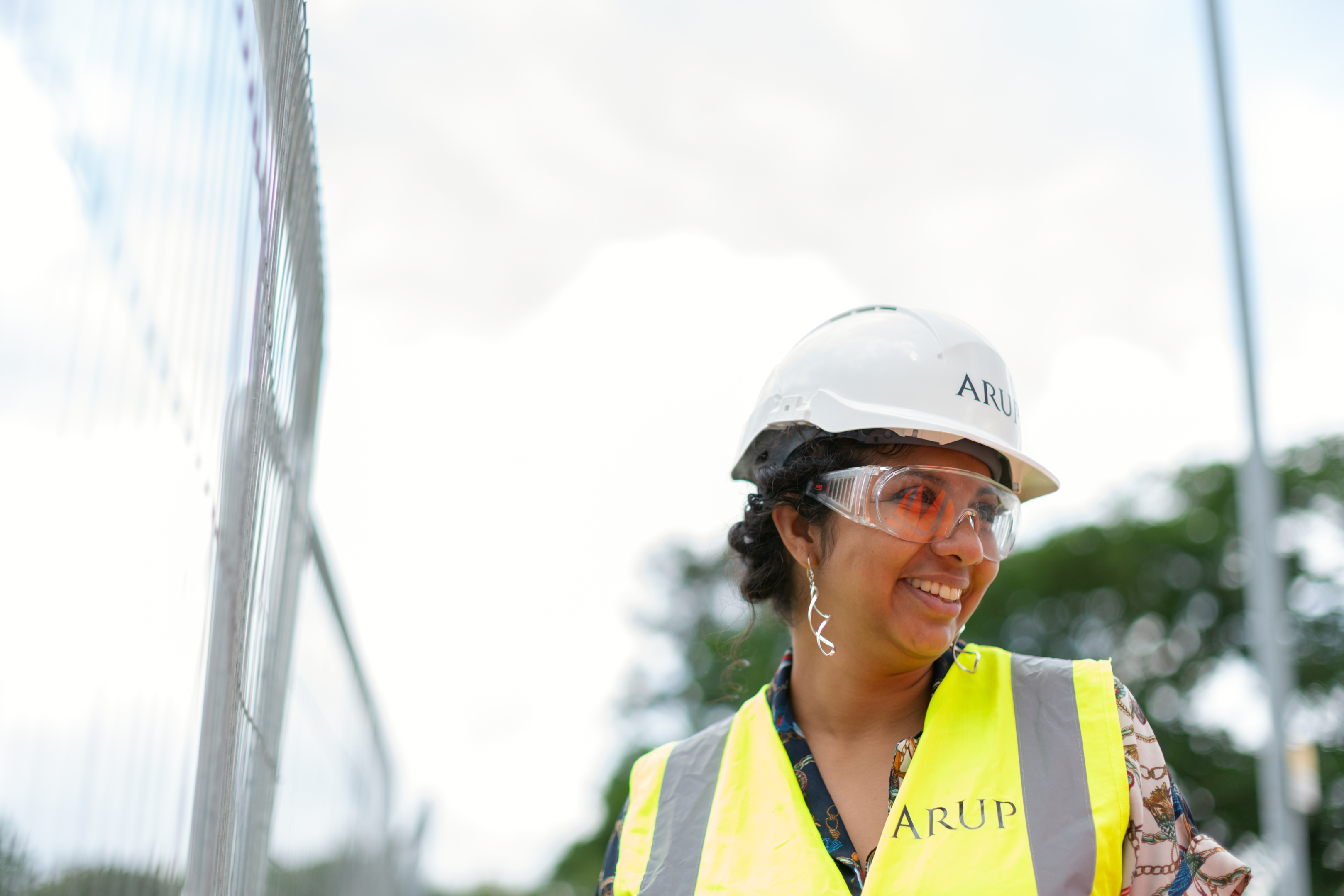 Woman dressed in hi-vis jacket, eye protection and hard hat