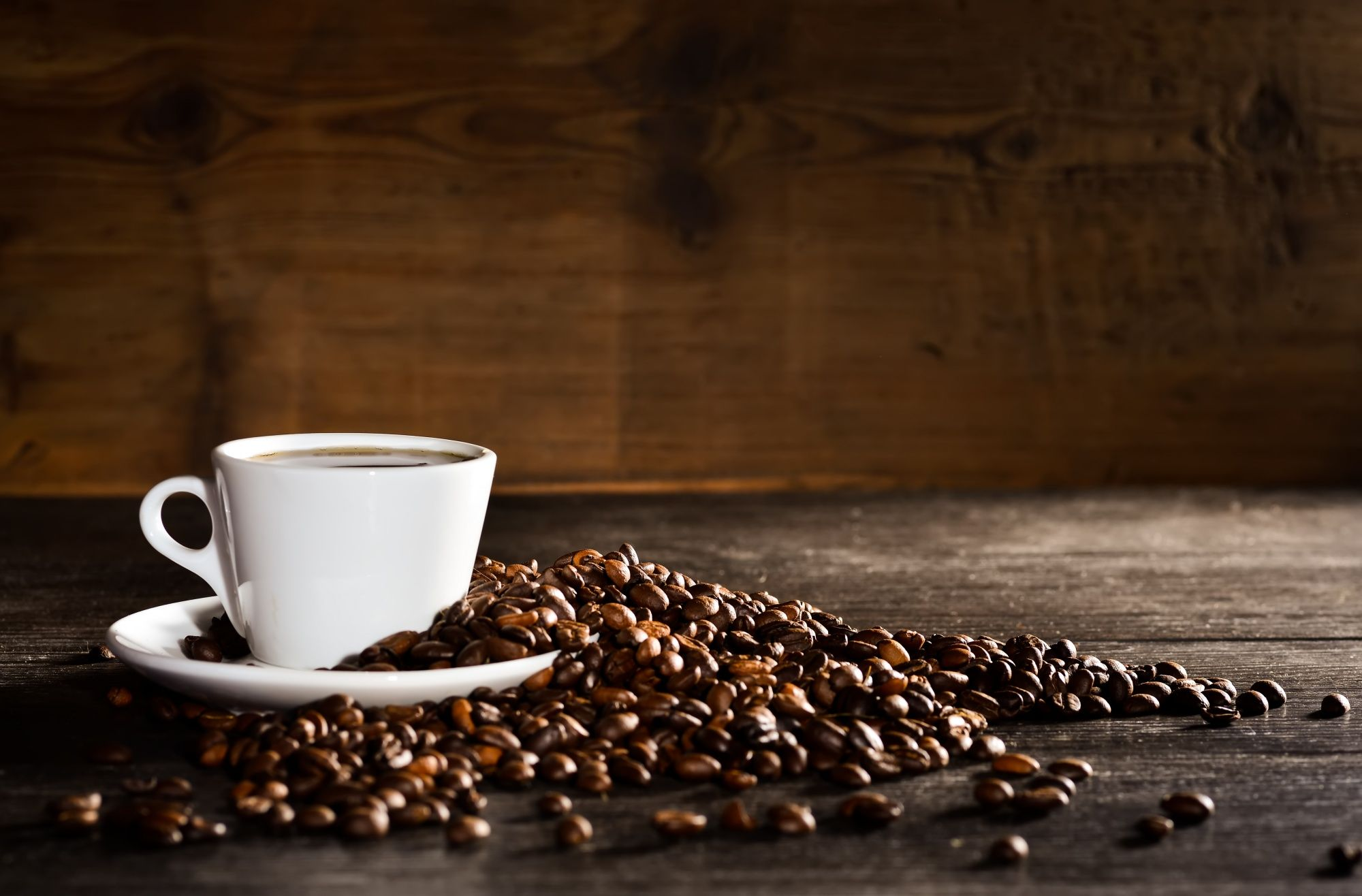 Brewed Coffee in a cup surrounded by freshly roasted coffee beans