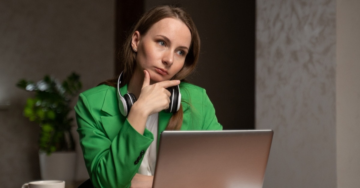 A woman in front of a laptop, thinking about what percentage do Onlyfans take?