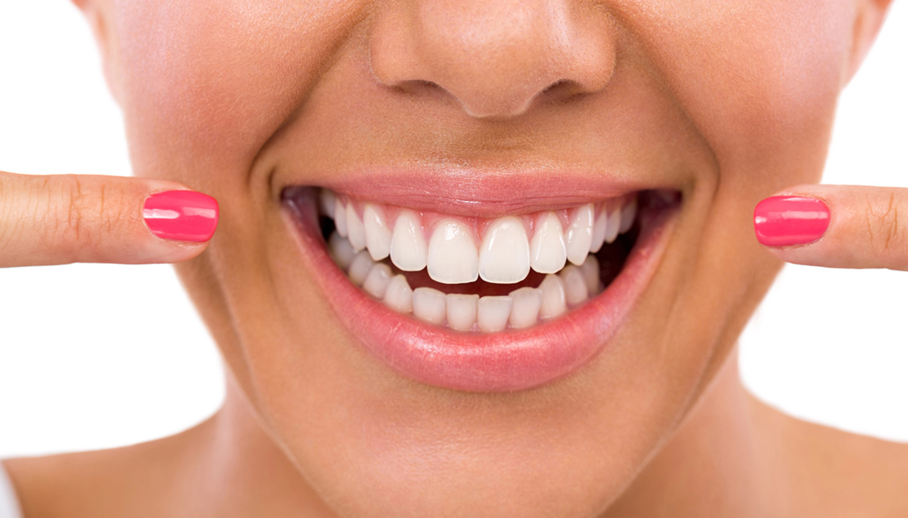 Tannbleking med Opalescence: Hvite Tenner Uten Risiko? 3 Kvinne med rosa neglelakk smiler bredt og peker på sine hvite, rene tenner fornøyd.