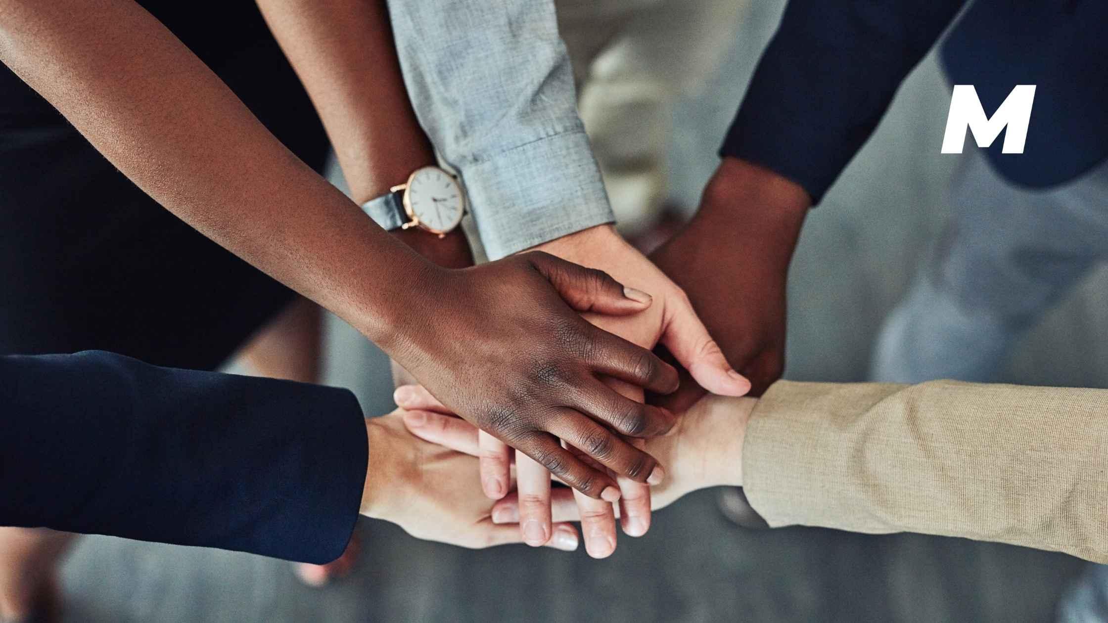 A team of colleagues placing their hands together 