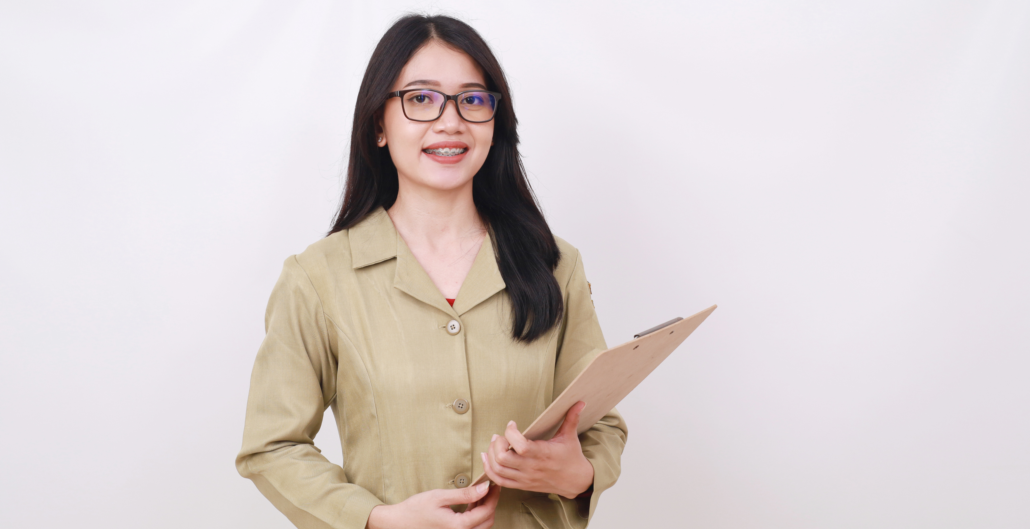 A woman in a beige blazer holding a clipboard and smiling. This image can represent a professional dedicated to OnlyFans bookkeeping services.