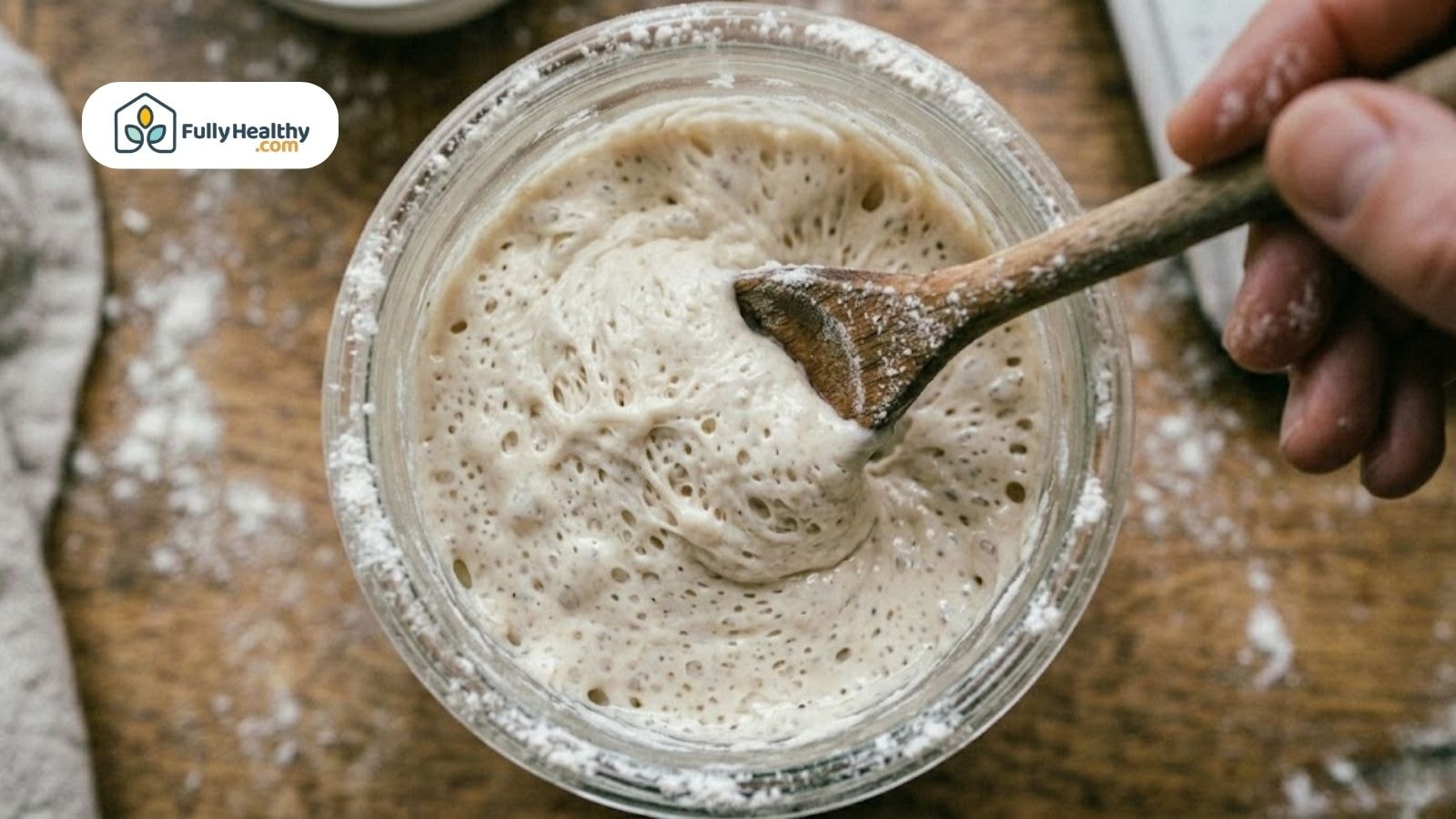 Close-up of active sourdough starter being stirred with a wooden spoon.