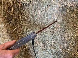 A hay probe tester being used to collect a sample from a bale of hay for analysis.