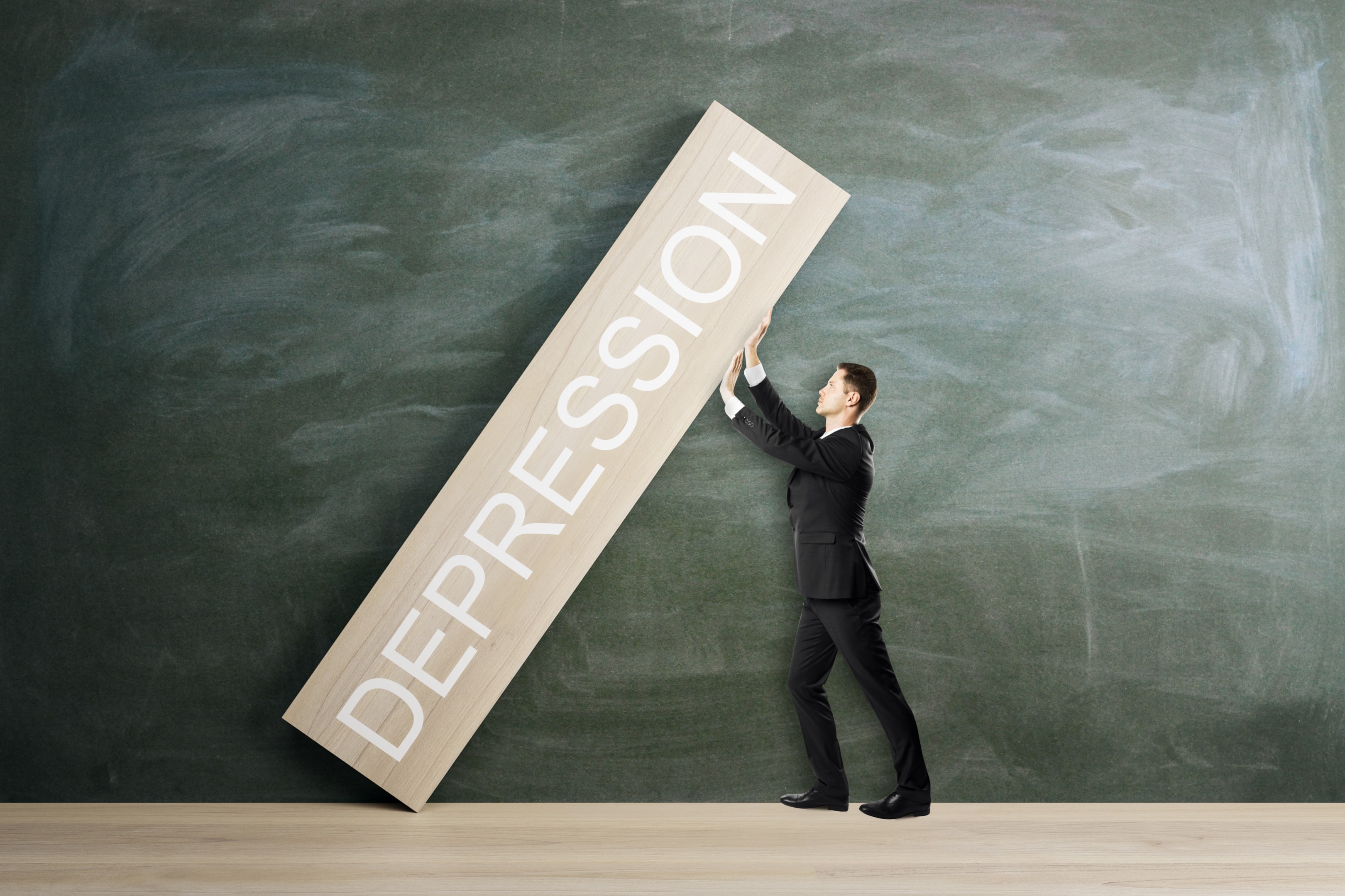 A man struggling to lift a heavy block labeled DEPRESSION illustrating the complex burden of Managing Depression Symptoms in The Woodlands