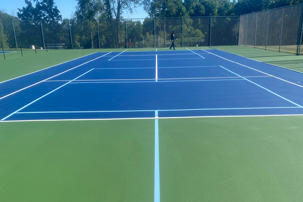 Multi-purpose court marked for both tennis and pickleball, featuring a smooth, dual-striped surface designed to accommodate multiple sports.