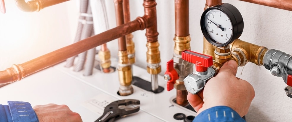 An image showing plumbing fixtures and a plumbing system with a plumber working to replace plumbing in a Big Bear home. 