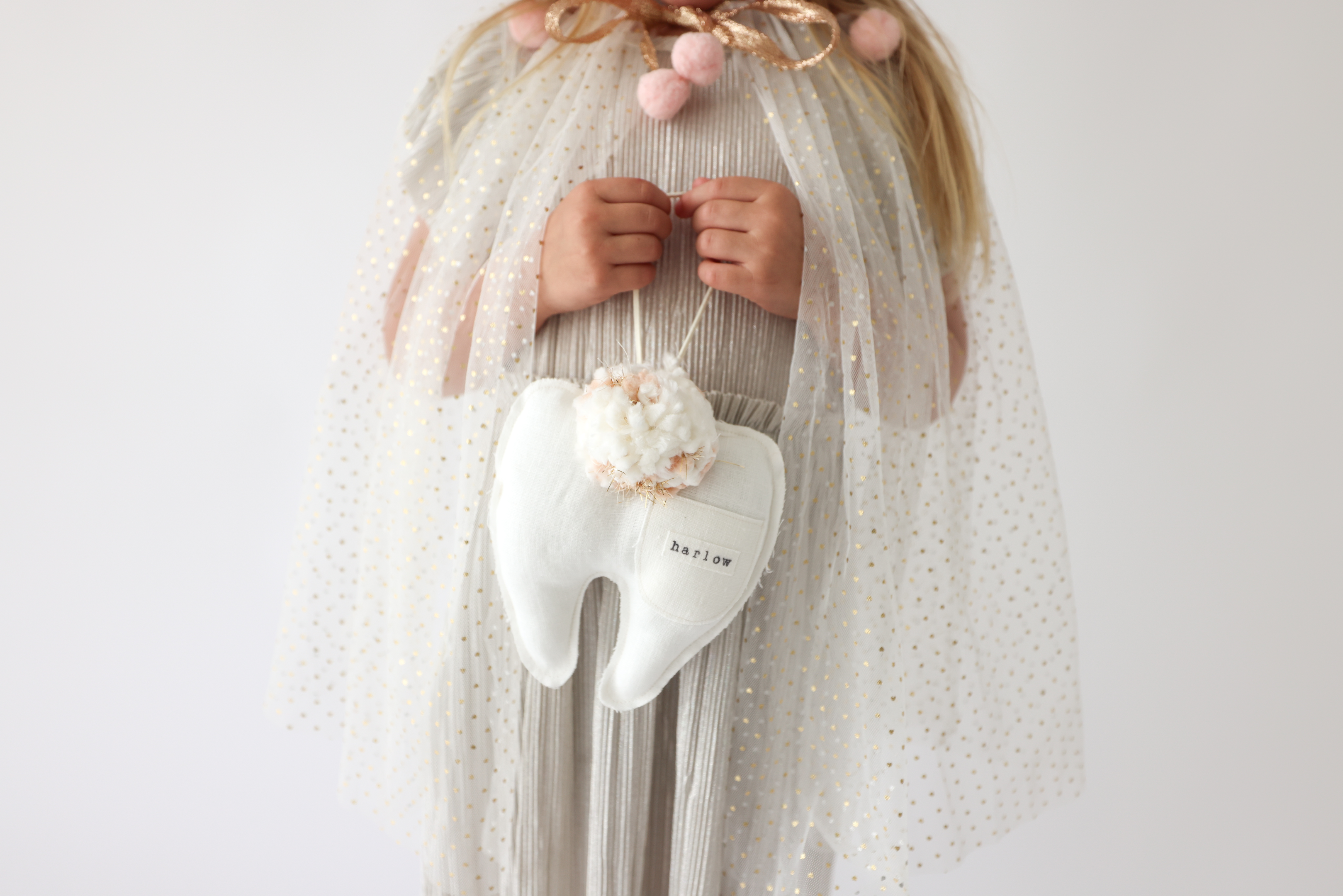 A child holding a tooth fairy keepsake pillow.