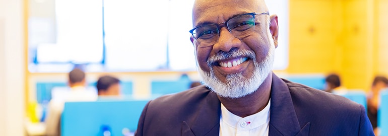 A man with glasses and a beard smiling at the camera