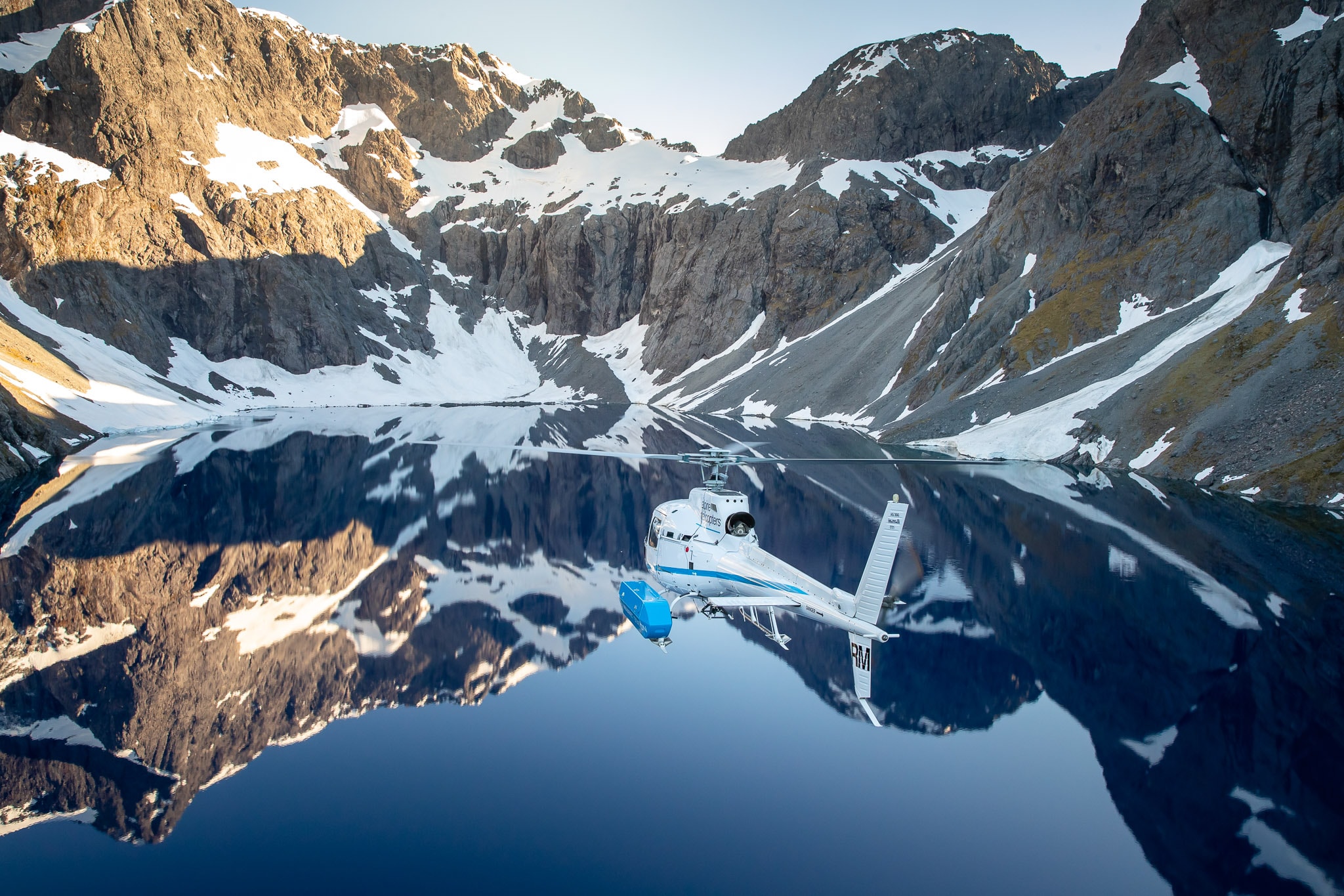 Scenic helicopter flight over pristine mountain lake surrounded by alpine peaks.