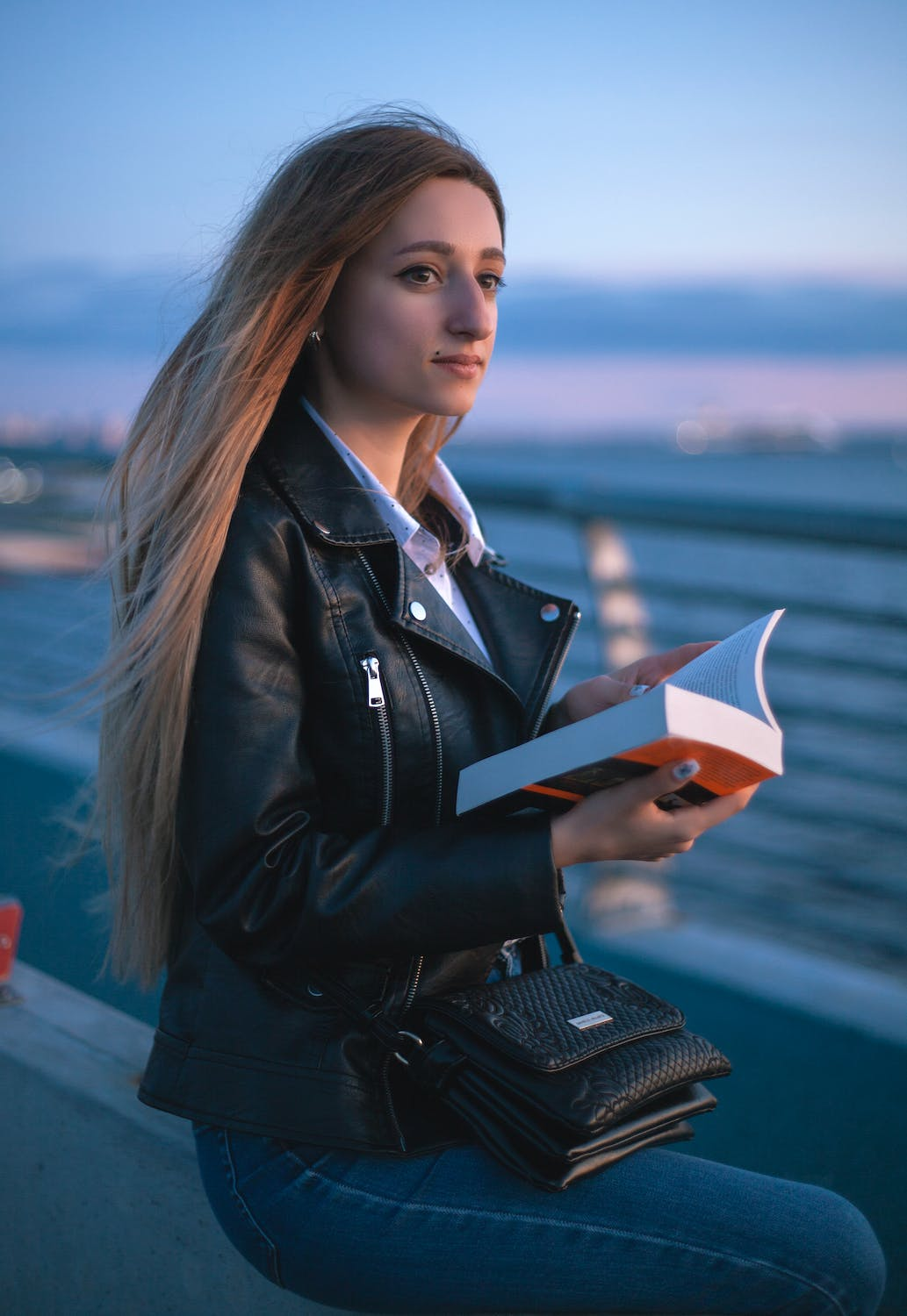 Mujer con chaqueta de cuero y libro en la mano