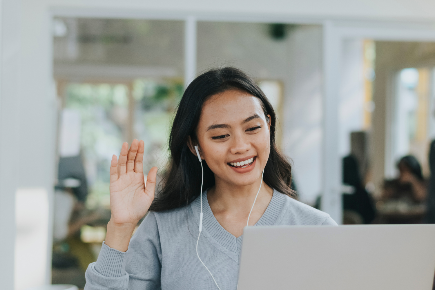 A Filipino interviewee waving on her laptop.