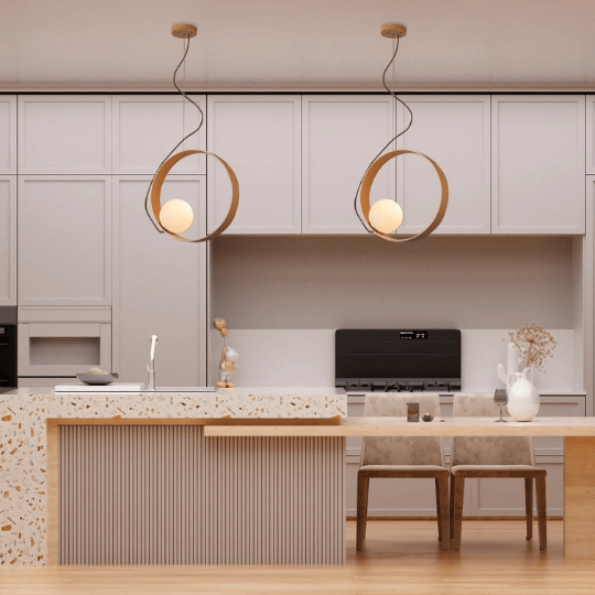 Modern kitchen with a terrazzo island and two barstools, illuminated by twin pendant lights featuring circular gold frames with glowing orb bulbs.