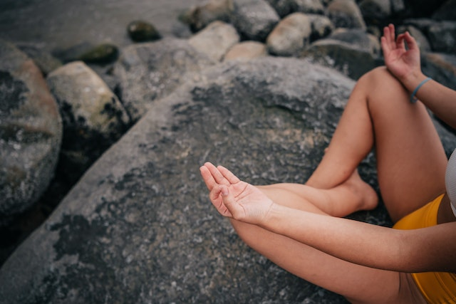 woman meditating on rocks - abundant mindset 