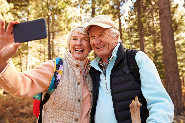 Cheerful older couple pausing for a selfie on a hike. 