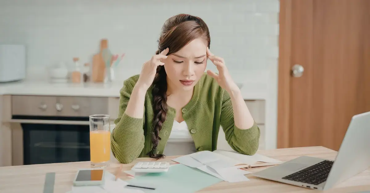 Woman reviewing bills on laptop while comparing charge-off vs. cancellation of debt.