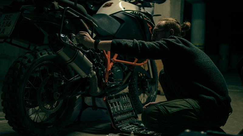 Man repairing motorcycle using toolkit