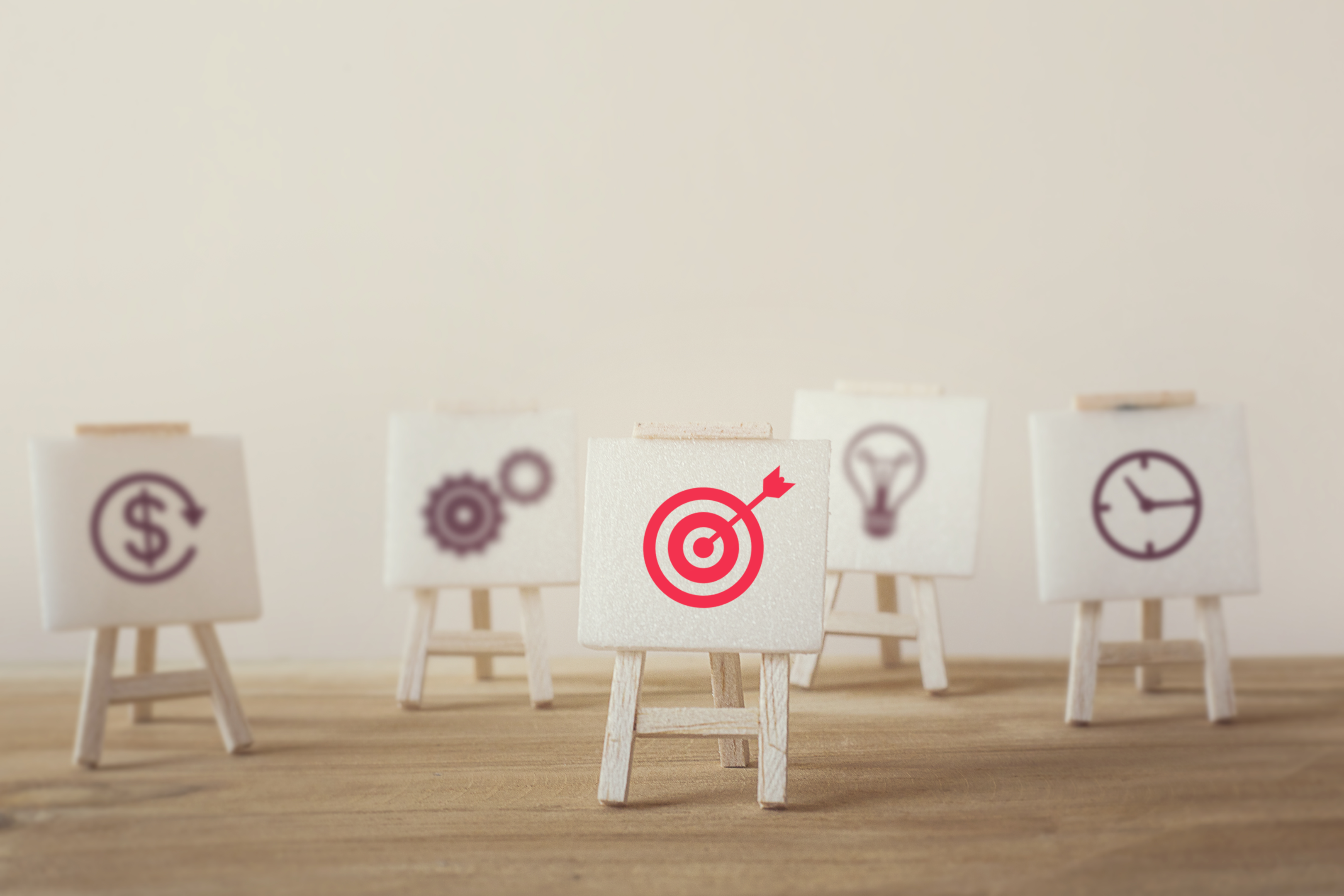 five miniature easels hold different marketing icons with one highlighted in red of a target 