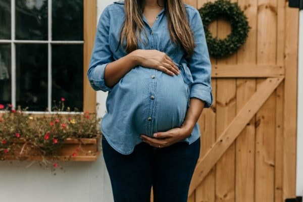 Pregnant woman holding her belly and wondering if she can get her wisdom teeth out while pregnant