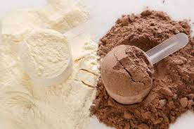 Two scoops of protein powder, one vanilla and one chocolate, on a surface.