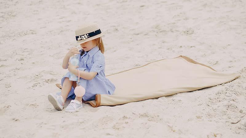 A child sitting on a beach towel