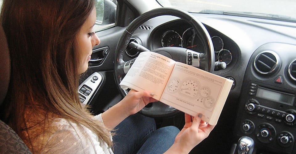 Person reading owner's manual for a specific vehicle