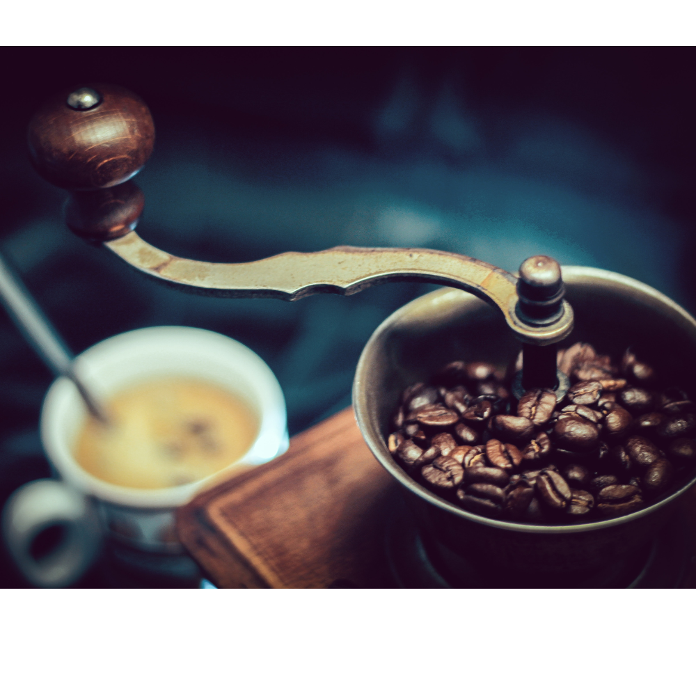 A cup of coffee with coffee beans and a coffee grinder