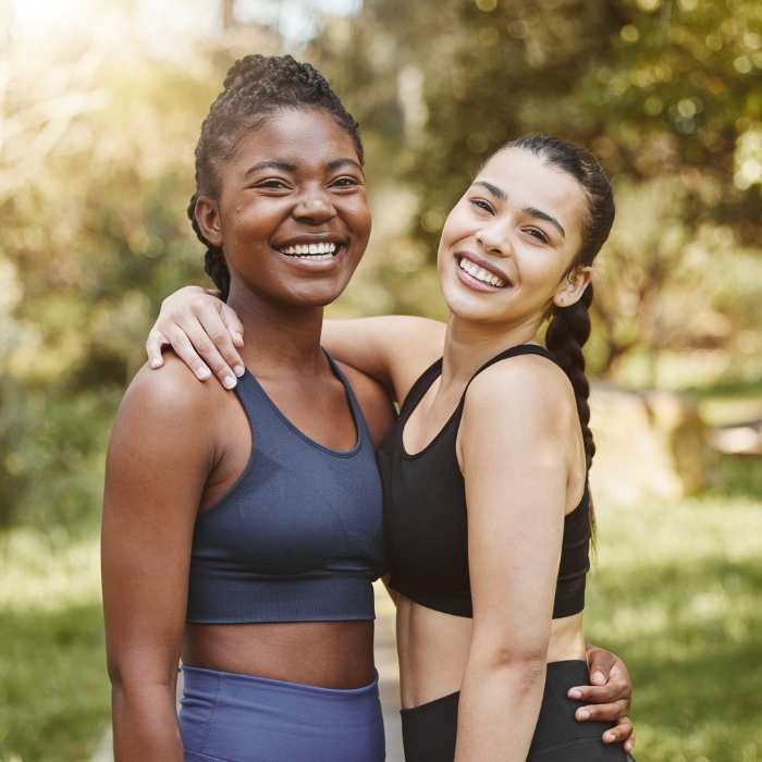 Benefits of B Vitamins - Two women embracing after a workout in the park.