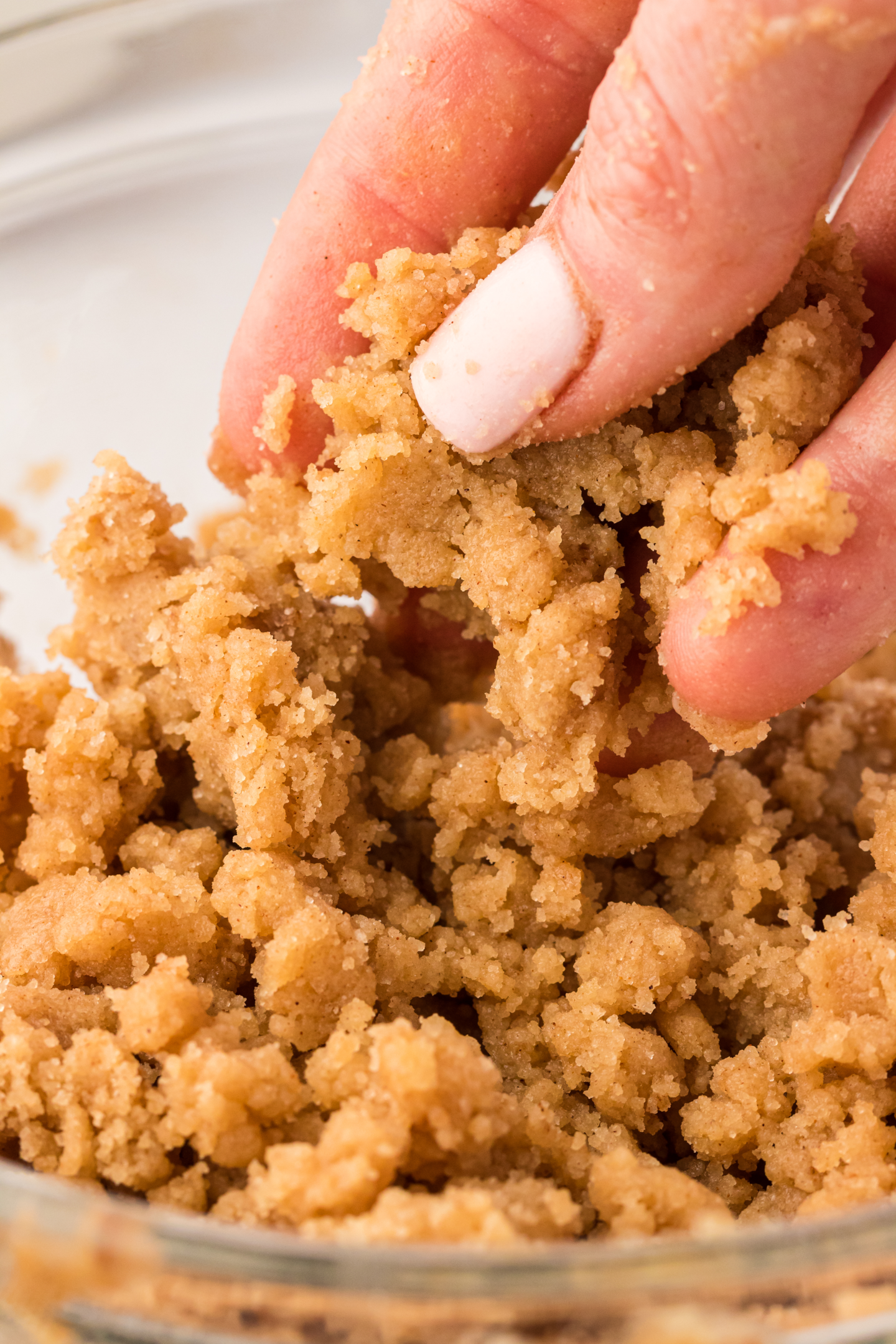 hand holding crumble topping in a bowl