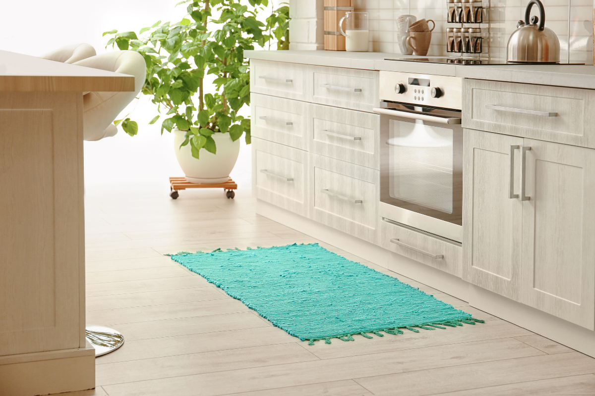 A rug pad being placed under a kitchen runner rug for maintenance