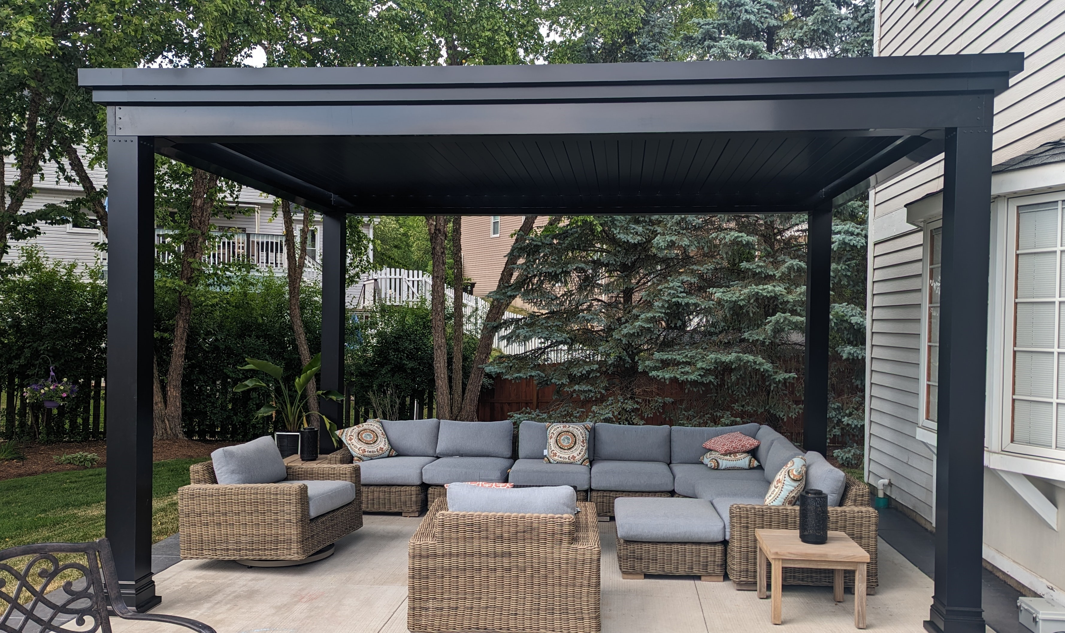 Patio with pergola casting shadow on outdoor living room under pergolas louvered roof.