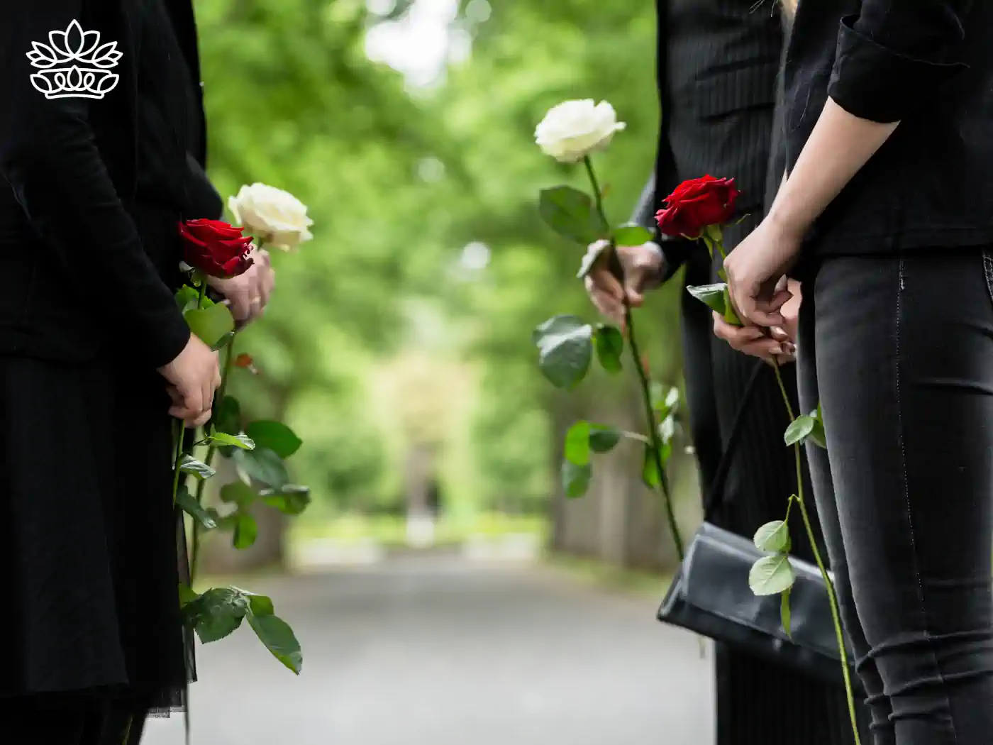 Mourners holding red and white roses at a graveside service. Fabulous Flowers and Gifts Funeral Collection.