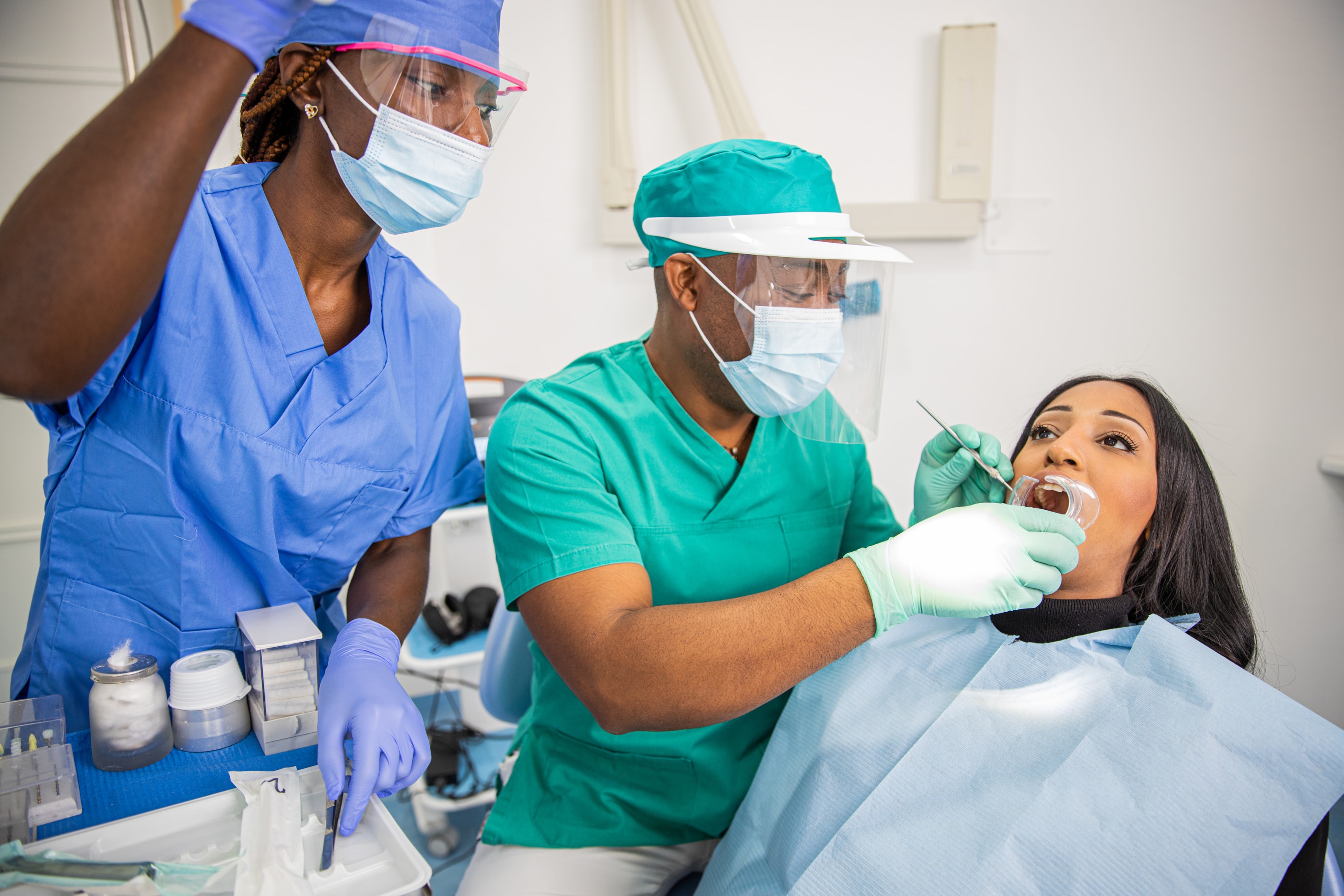 A woman being examined in a dental chair by an oral surgeon and assistant 