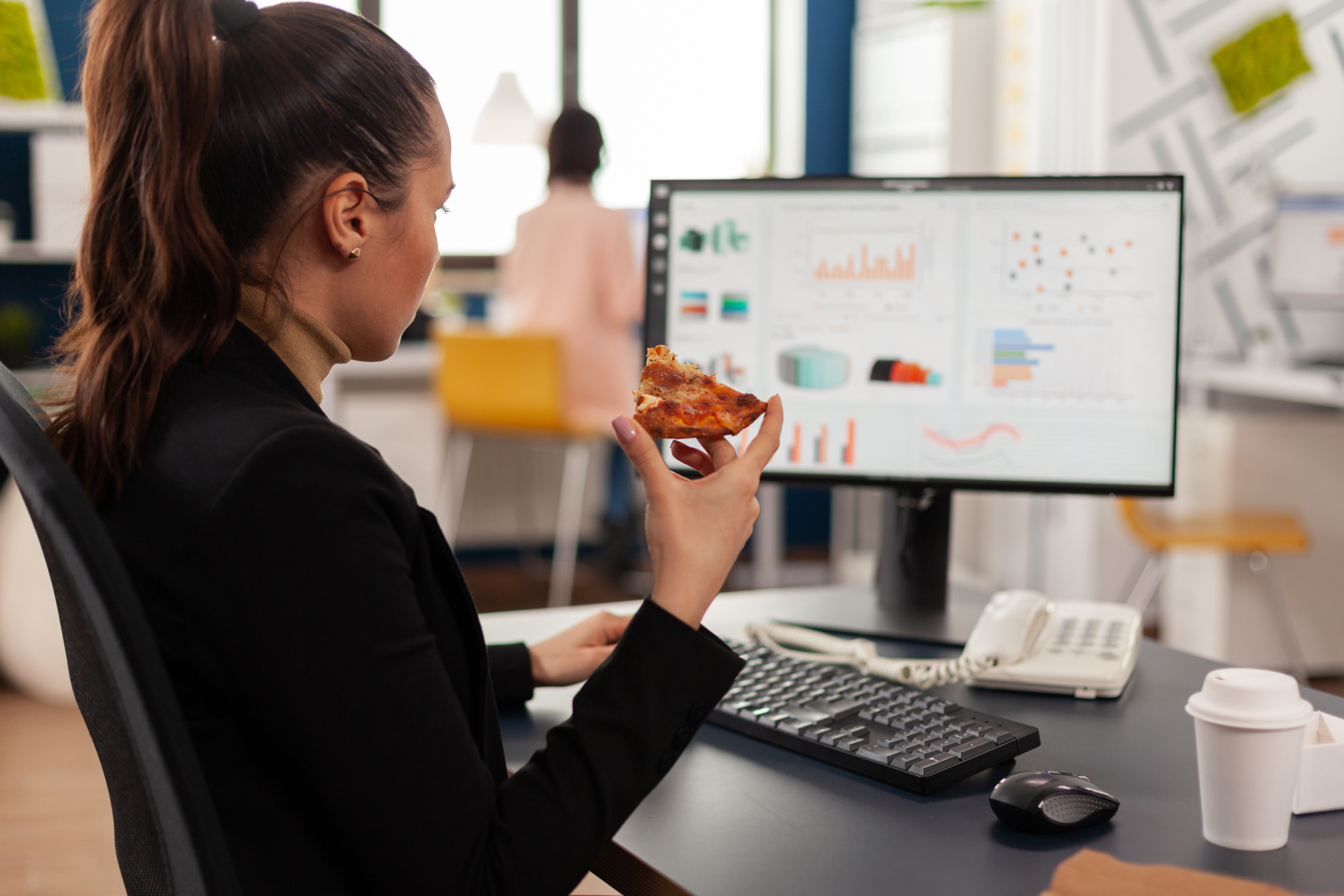 "A businesswoman savors a break with takeout lunch amidst a busy day - a moment that speaks to California's regulations on mandatory meal breaks for employees."