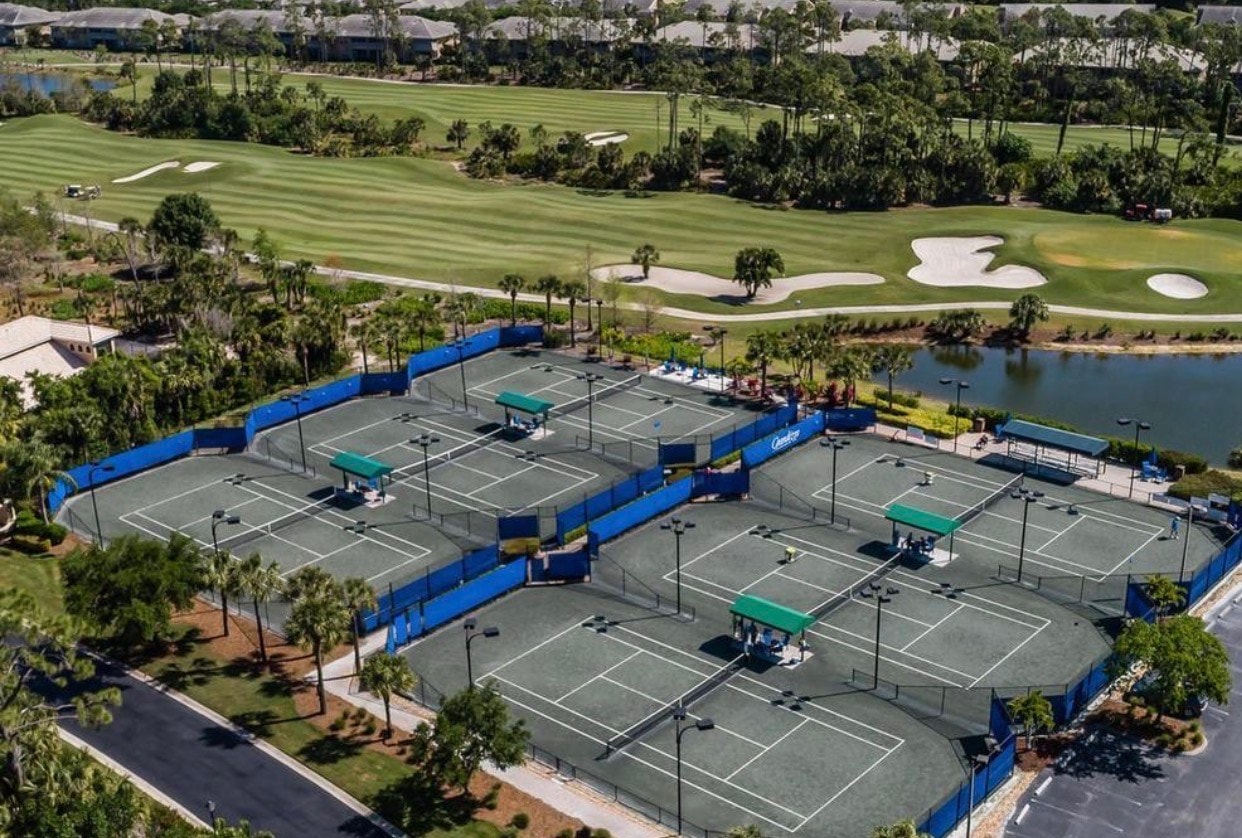 The image depicts a row of elegant coach homes nestled within a beautifully landscaped gated community in Estero, FL, featuring detached garages and vibrant greenery. This serene neighborhood offers convenient access to amenities such as golf courses and fitness centers, embodying the charm of the Florida Gulf Coast.