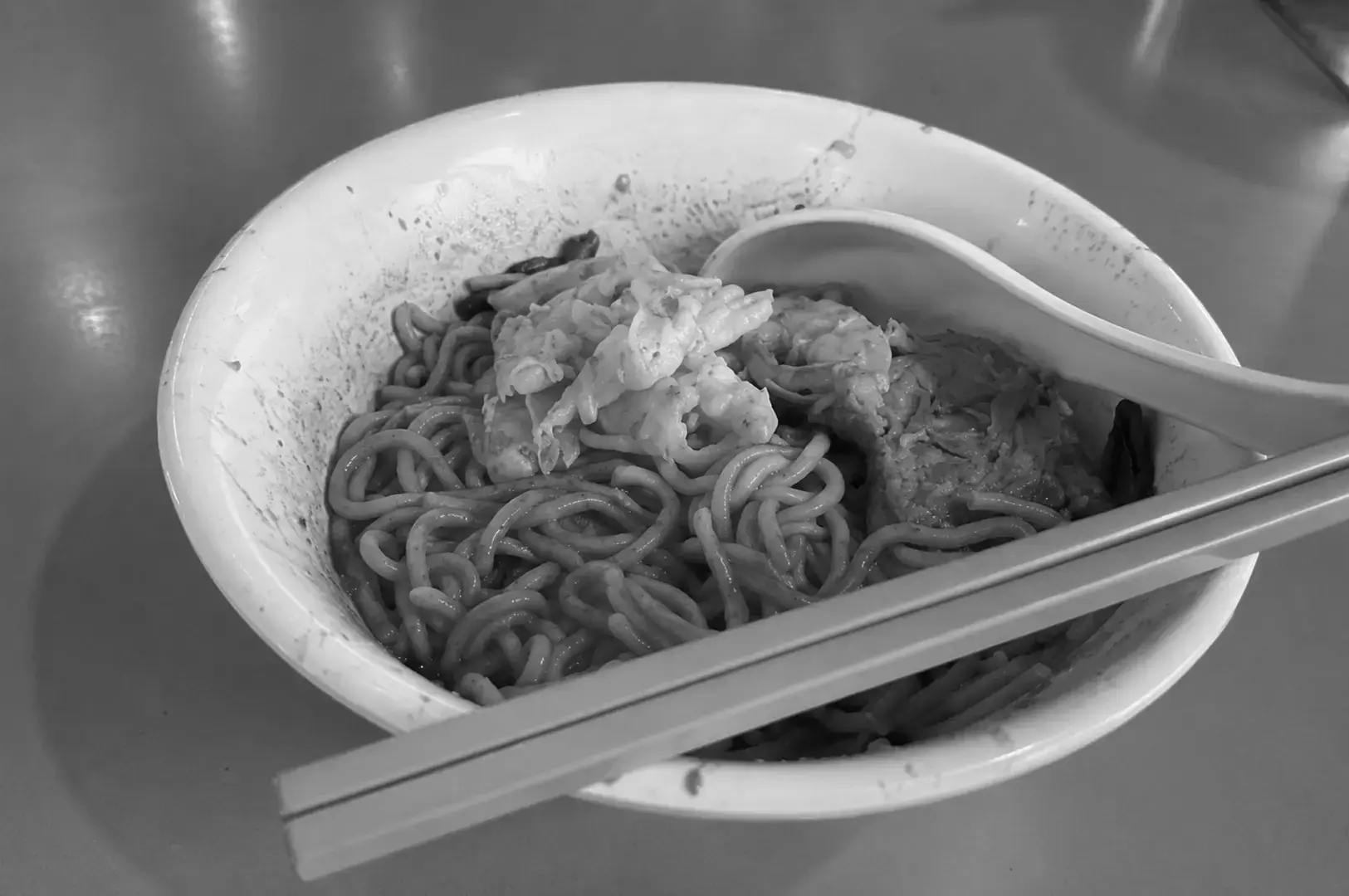 Bowl of dry noodles topped with prawns and minced meat, ready to eat.