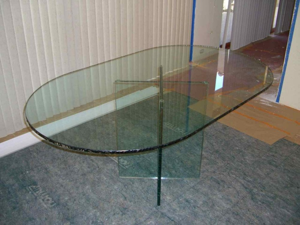 A stunning glass racetrack oval table dining table, with a custom chipped edge.  Perfect for creating a focal point and visual appeal in your dining room.