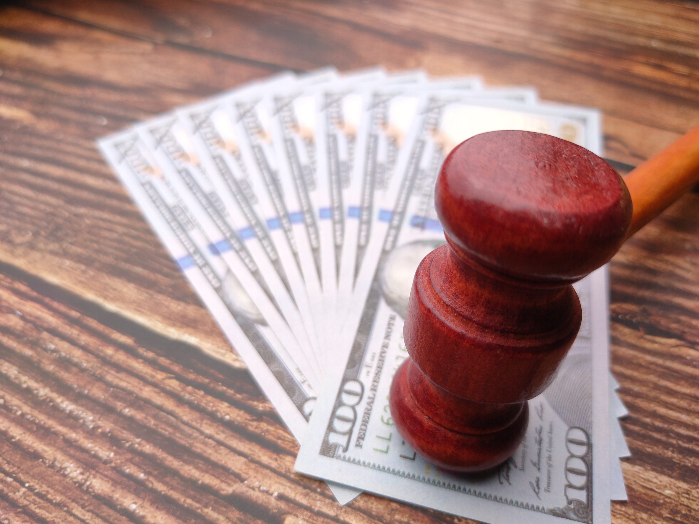 A fan of cash with a red gavel sitting on top