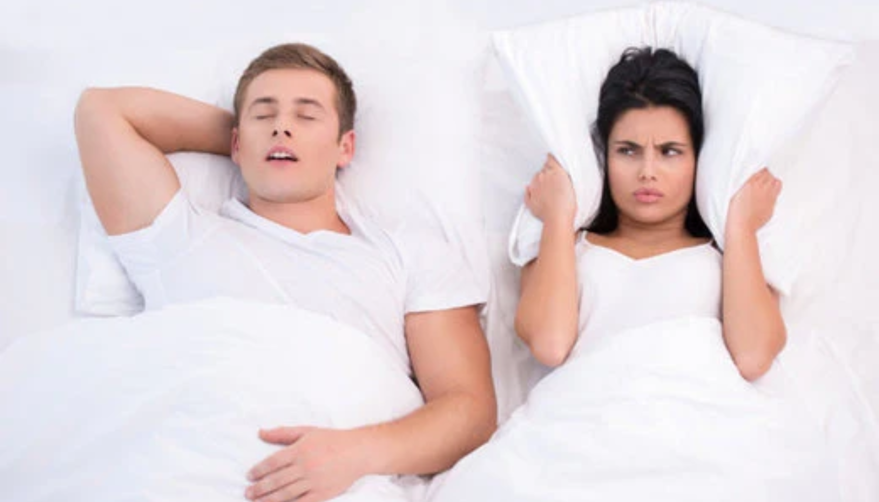 Snorkeskinne: Liten Skinne, Stor Effekt på Søvnen 18 Mann snorker høyt i seng mens kvinne ved siden av ser frustrert ut og holder pute over hodet.