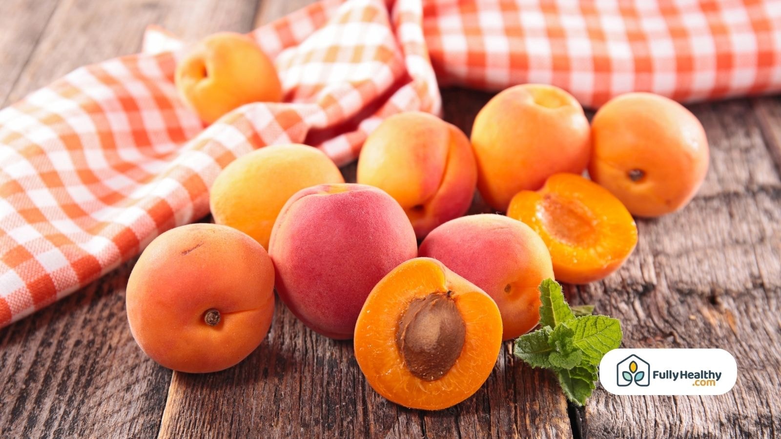 Apricots halved on a wooden surface with fresh mint leaves