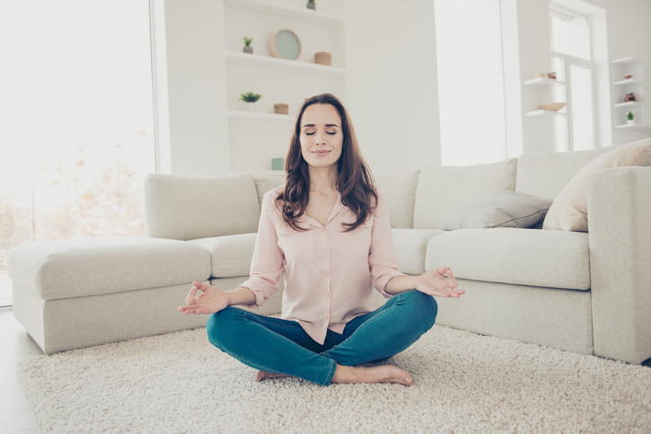 Woman slowing down, sitting on floor and meditating. Sending love vibrations.