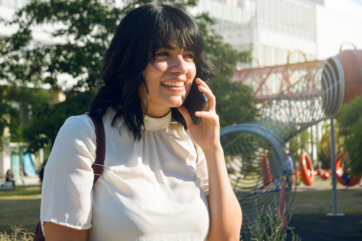 Young woman with dark hair talking on a cell phone. 