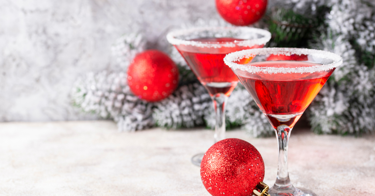 Festive holiday cocktails at a Jersey Shore Christmas pop-up bar, featuring red martinis with sugared rims surrounded by Christmas ornaments and winter greenery for seasonal NJ holiday events.